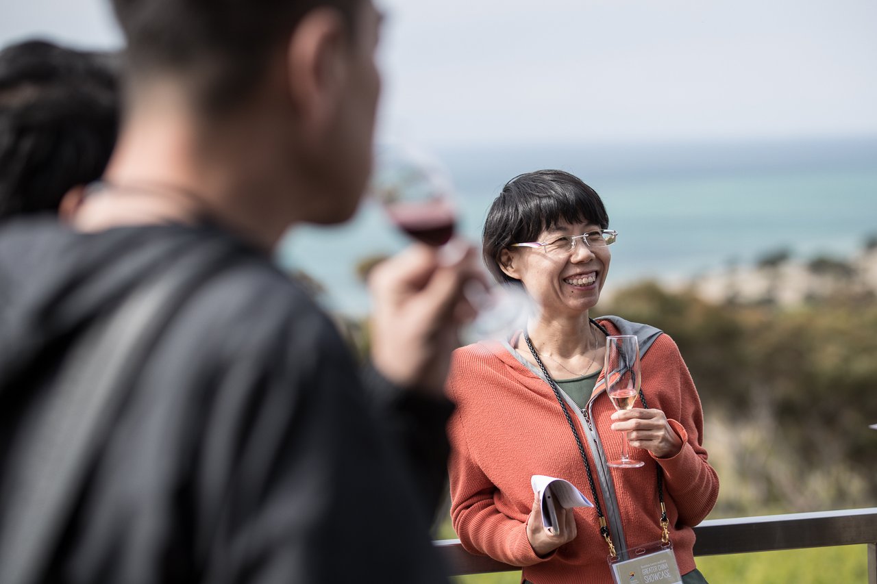 Woman enjoying a glass of wine at Jack Rabbit Winery, the bay is visible in the background. 