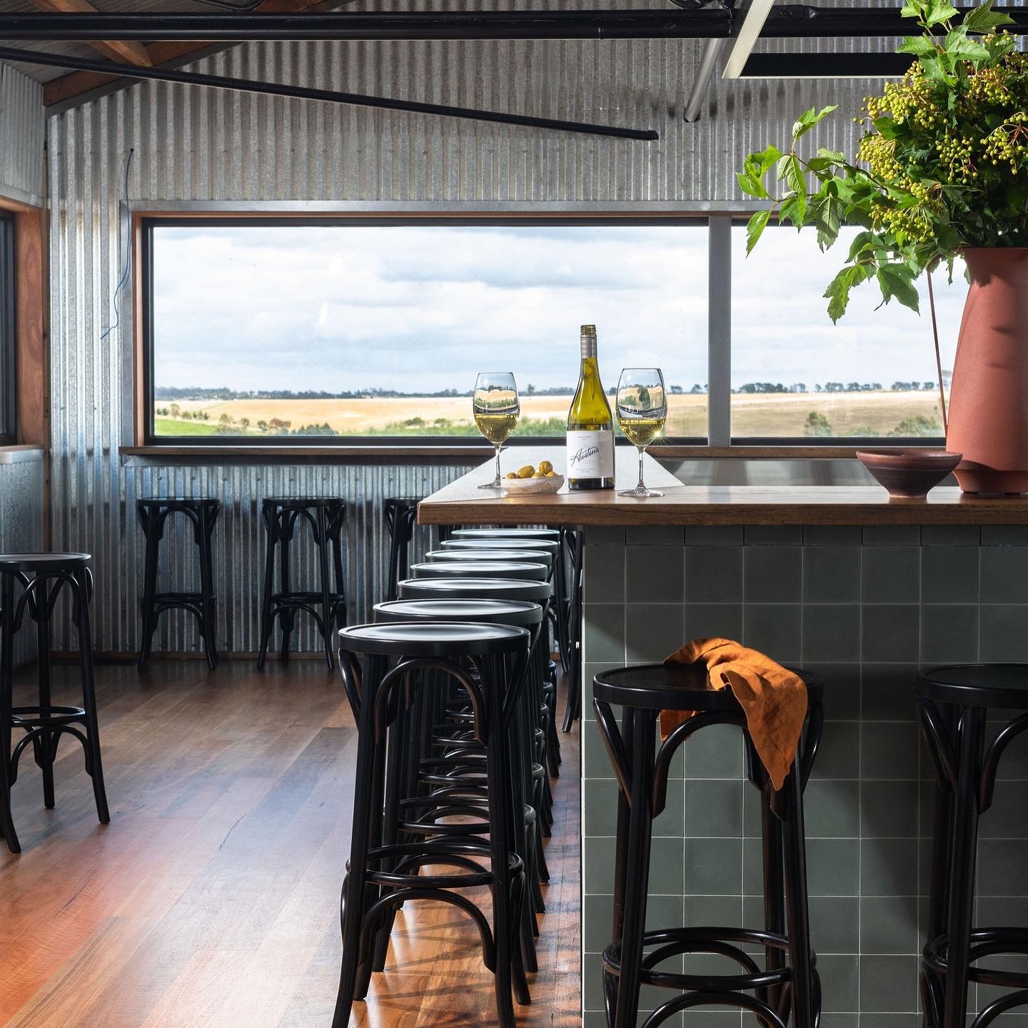 Inside a cellar door. Barstools line a blue tiled bar and the far wall below the window, which overlooks stunning rural views.