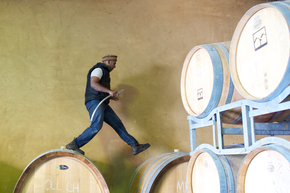 A man steps between two wine barrels.